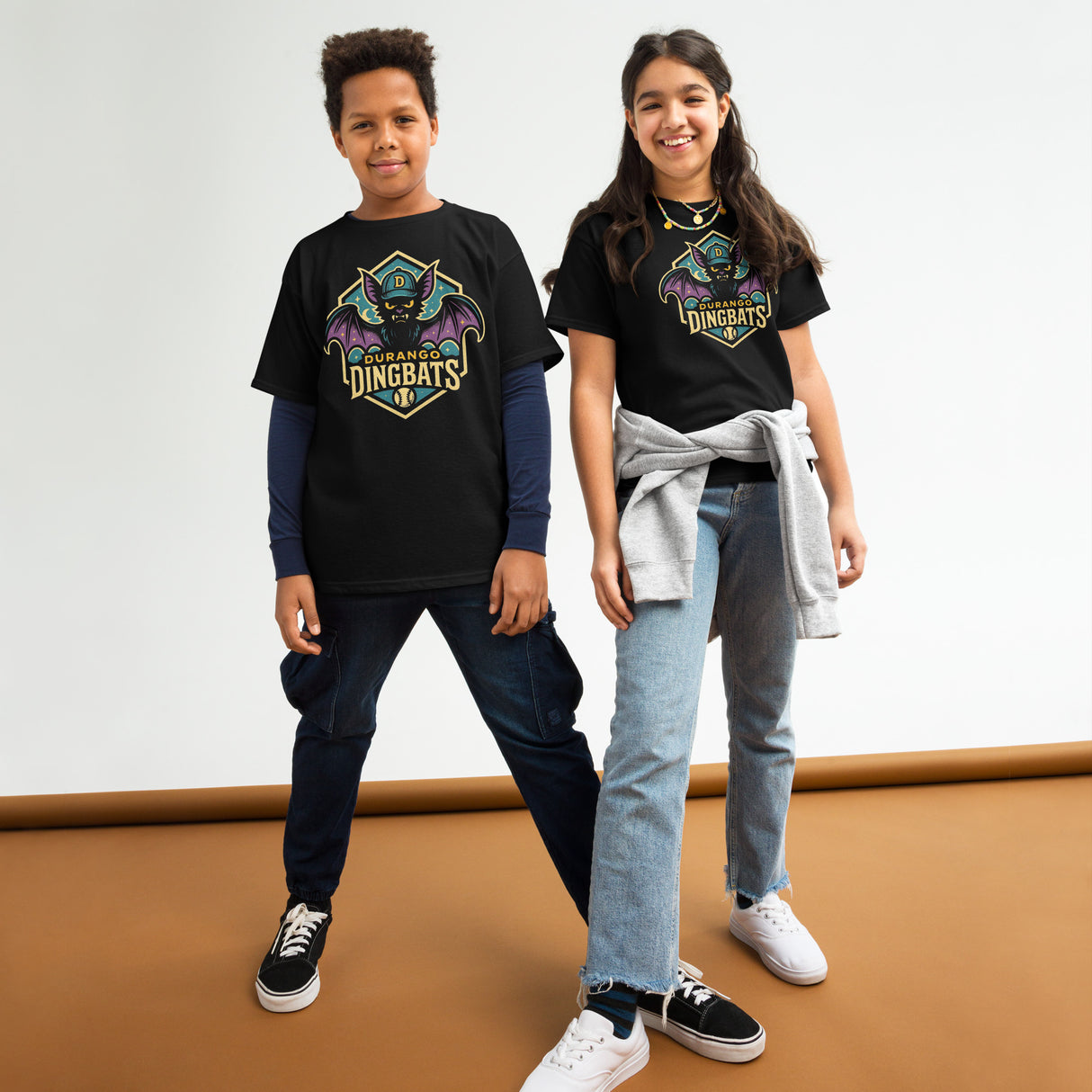 Young boy and girl smiling and wearing black Durango Dingbats retro-style baseball t-shirts with bold bat mascot, part of Outfield Outlaws' vintage minor league collection.