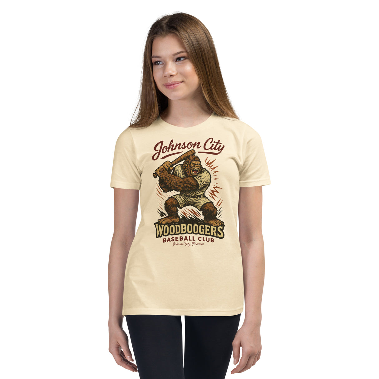 Youth girl model wearing Johnson City Woodboogers youth baseball t-shirt in natural featuring cryptid mascot design