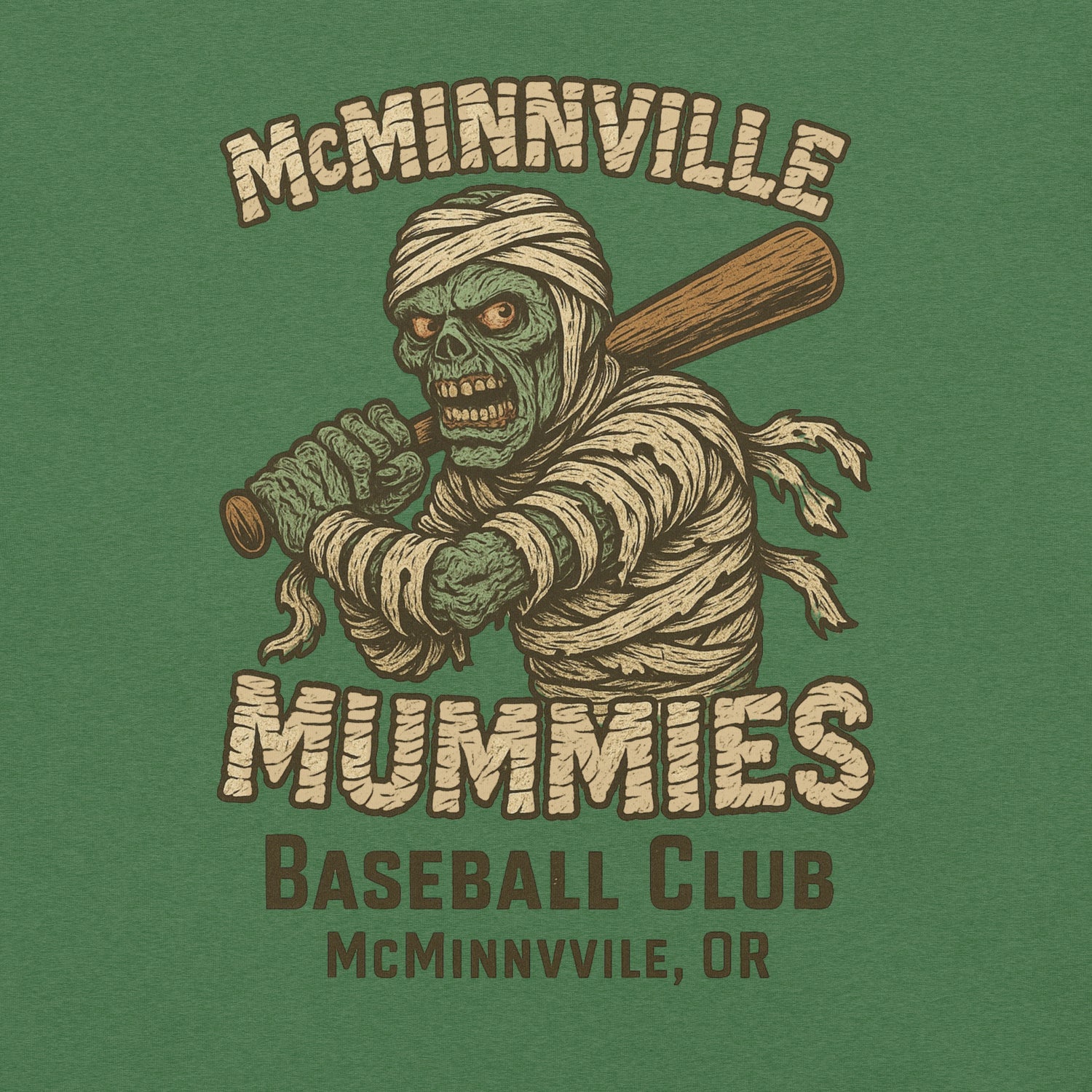 Close-up of McMinnville Mummies tee in heather grass green, highlighting distressed mummy mascot and retro baseball print.