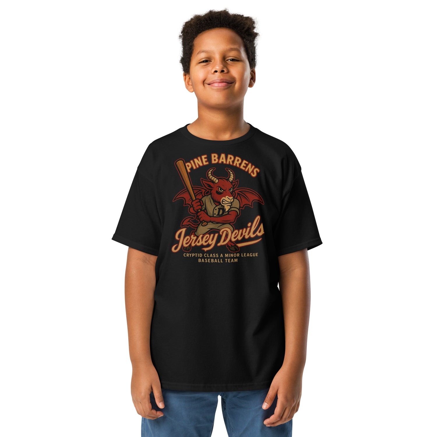 Smiling young boy wearing the Pine Barrens Jersey Devils youth t-shirt in black, featuring a vintage-style red cryptid mascot with a bat.